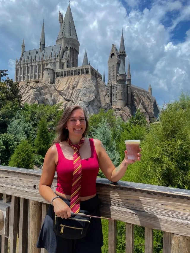 Photo of girl wearing a Gryffindor themed outfit standing in front of Hogwarts castle at Universal Studios Florida.